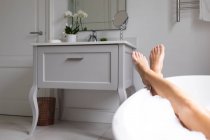 Nahaufnahme einer Frau, die mit überkreuzten Beinen in der Badewanne liegt — Stockfoto