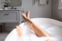 Nahaufnahme einer Frau, die mit überkreuzten Beinen in der Badewanne liegt — Stockfoto