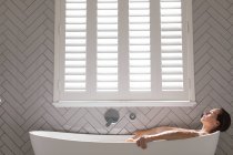 Femme relaxante dans la baignoire dans la salle de bain à la maison — Photo de stock