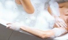 Seção média de mulher tomando banho na banheira no banheiro — Fotografia de Stock