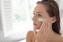 Primer plano de la mujer que aplica mascarilla facial después de bañarse - foto de stock