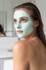 Крупним планом жінка в масці для обличчя дивиться у ванну кімнату — стокове фото
