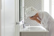 Frau wäscht ihre Gesichtsmaske im Waschbecken des Badezimmers zu Hause — Stockfoto