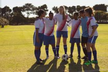 Front view of diverse female soccer players getting ready to play soccer at sports field on a sunny day. — Stock Photo