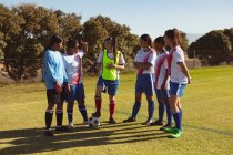 Вид спереди различных женщин-футболистов, взаимодействующих друг с другом на спортивном поле в солнечный день — стоковое фото