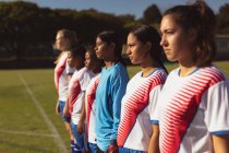Side view of diverse female soccer players standing in row at the sports field on sunny day — Stock Photo