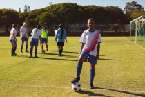 Ritratto di diverse giocatrici di calcio con palla in piedi in un campo sportivo in una giornata di sole — Foto stock