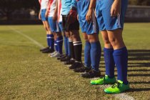 Seção média de jogador de futebol feminino em pé em fila no campo de esportes no dia ensolarado — Fotografia de Stock