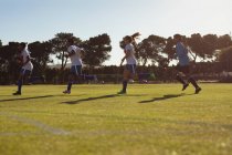 Vista de bajo ángulo de diversas jugadoras de fútbol corriendo en el campo de deportes en un día soleado - foto de stock