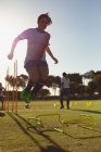 Tiefansicht einer kaukasischen Fußballerin, die während des Trainings auf dem Sportplatz über Hürde springt — Stockfoto