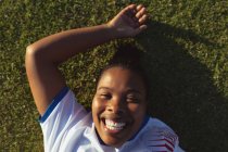 Портрет щасливого афро-американського жіночого футбольного плеєра відпочиваючи на полі в сонячний день — стокове фото