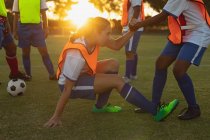 Vista lateral de diversas jogadoras de futebol fazendo exercícios de aquecimento no campo esportivo durante o torneio — Fotografia de Stock