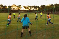 Visão traseira de determinadas diversas jogadoras de futebol que jogam no campo esportivo — Fotografia de Stock