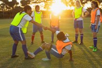 Vue latérale de diverses joueuses de soccer faisant des exercices d'échauffement sur le terrain de sport pendant le tournoi — Photo de stock