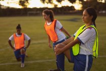 Вид на різні жінки футбольні гравці роблять розминки вправи на спортивному полі — стокове фото