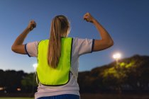Rear view of Caucasian female soccer player cheering after victory at sports field — Stock Photo