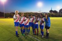 Вид спереду на різноманітну жіночу футбольну команду, що позує з медаллю на спортивному полі — стокове фото