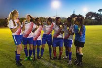 Вид з різноманітної жіночої футбольної команди показані медаль один з одним у спортивному полі — стокове фото
