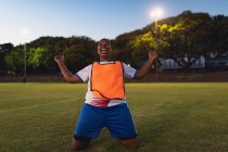 Vue de face du footballeur afro-américain insouciant acclamant après la victoire sur un terrain de sport — Photo de stock