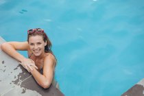 Portrait of happy Caucasian woman standing at the edge of swimming pool — Stock Photo