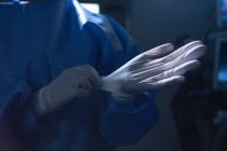 Mid section of female surgeon with surgical gloves in operation room in hospital — Stock Photo