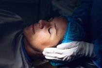 Cierre de cirujano que reconforta a la mujer embarazada durante el parto en quirófano en el hospital - foto de stock