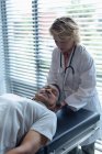 Vue de face du médecin féminin caucasien examinant le cou de patient masculin mixte senior à l'hôpital — Photo de stock