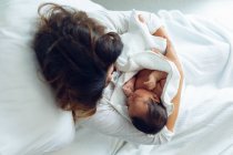 Вид сверху на красивую кавказскую мать, держащую новорожденного ребенка после родов в палате больницы — стоковое фото