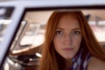 Замкнутый круг красивой молодой белой женщины, смотрящей на камеру в фургоне на пляже — стоковое фото