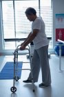 Side view of mixed race male patient walking with walker in the ward at hospital — Stock Photo
