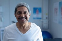 Retrato del paciente masculino de raza mixta sonriendo en la sala del hospital - foto de stock