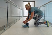 Vista laterale della paziente caucasica disabile con lacci protesici per le scarpe in corridoio in ospedale — Foto stock