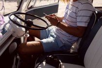 Sezione media del giovane utilizzando il telefono cellulare in furgone in spiaggia — Foto stock