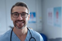 Portrait de chirurgien homme caucasien mature avec stéthoscope autour du cou regardant la caméra à l'hôpital — Photo de stock
