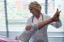 Вид спереди счастливой белой женщины-врача, осматривающей ногу пациента в больнице — стоковое фото