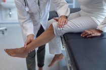 Низький відділ жіночого лікаря, який оглядає ногу пацієнтки в лікарні — стокове фото