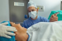 Vue de face de l'homme caucasien réconfortant la femme enceinte pendant le travail en salle d'opération à l'hôpital — Photo de stock