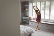 Vista posteriore della donna caucasica allungando la mano al mattino in camera da letto a casa — Foto stock
