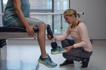 Вид збоку Кавказького жіночого фізіотерапевта коригування протезів нога жіночого пацієнта в лікарні — стокове фото