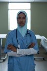 Портрет красивой женщины-врача смешанной расы в хиджабе, стоящей со скрещенными руками и стетоскопом на шее в больнице — стоковое фото