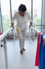 Frontansicht einer Patientin, die mit parallelen Stangen im Krankenhaus läuft — Stockfoto