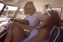 Вид збоку щасливої молодої пари Різноманітні розваги на передньому сидінні фургона на пляжі — стокове фото
