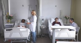 Вид спереду різноманітних лікарів, що взаємодіють з пацієнтами в лікарні — стокове фото