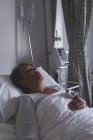 Vista frontale della paziente matura di razza mista che dorme nel letto del reparto in ospedale — Foto stock