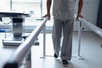 Bassa sezione di paziente maschio che cammina con barre parallele in ospedale — Foto stock