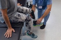 Niedriger Abschnitt des männlichen Physiotherapeuten, der die Beinprothese der Patientin im Krankenhaus anpasst — Stockfoto