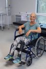 Vista frontale della paziente caucasica felice disabile che guarda la macchina fotografica in sedia a rotelle in ospedale — Foto stock