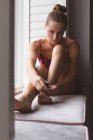Вид на Кавказьку жінку застосування лаку для нігтів її нігті сидячи на вікні сидіння в спальні будинку — стокове фото