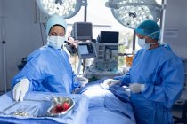 Бічний погляд на різноманітні жінки-хірурги, що виконують операцію в операційний номер в лікарні — стокове фото