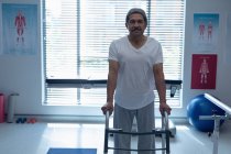 Front view of mixed race male patient walking with walker in the ward at hospital — Stock Photo